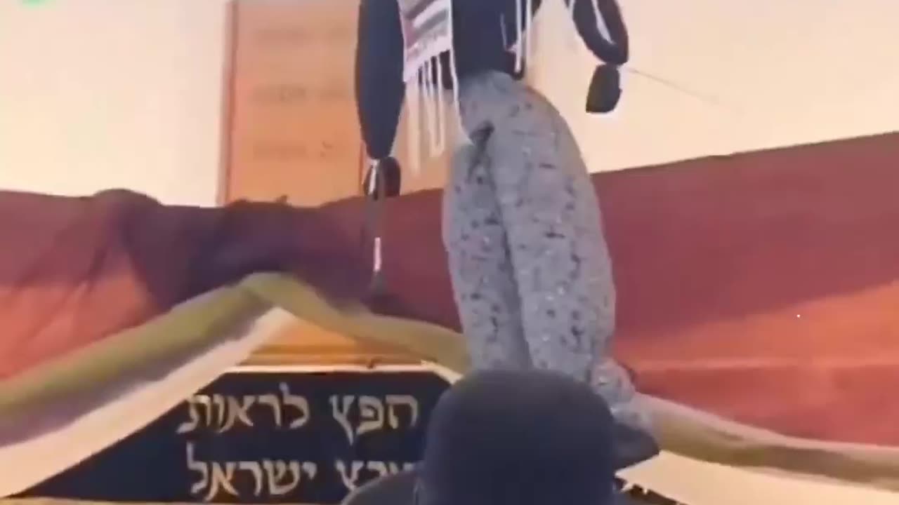 Israeli settlers celebrating as they hang a doll adorned with a Palestinian Kefiyyeh