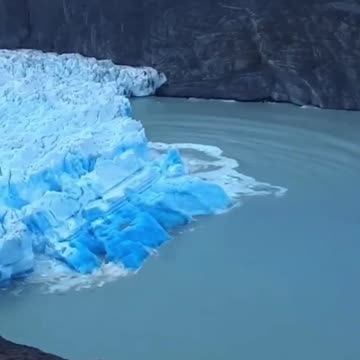 Rare sighting of the deep blue underside of a glacier during a collapse caused by glacier caving