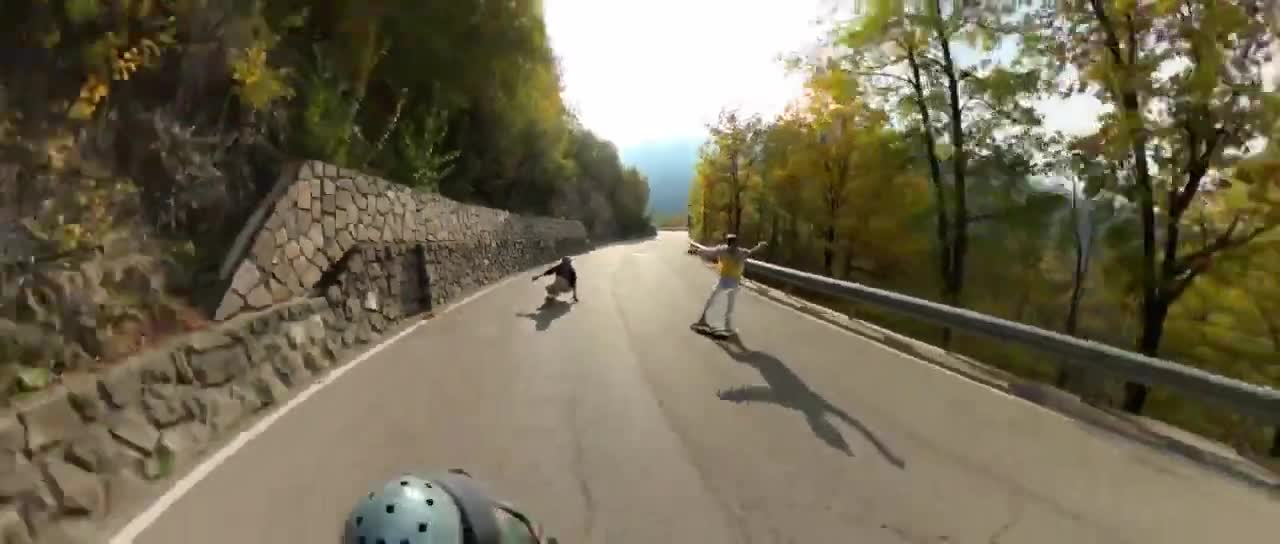 Men Perform Tricks Enroute Downhill on Longboards