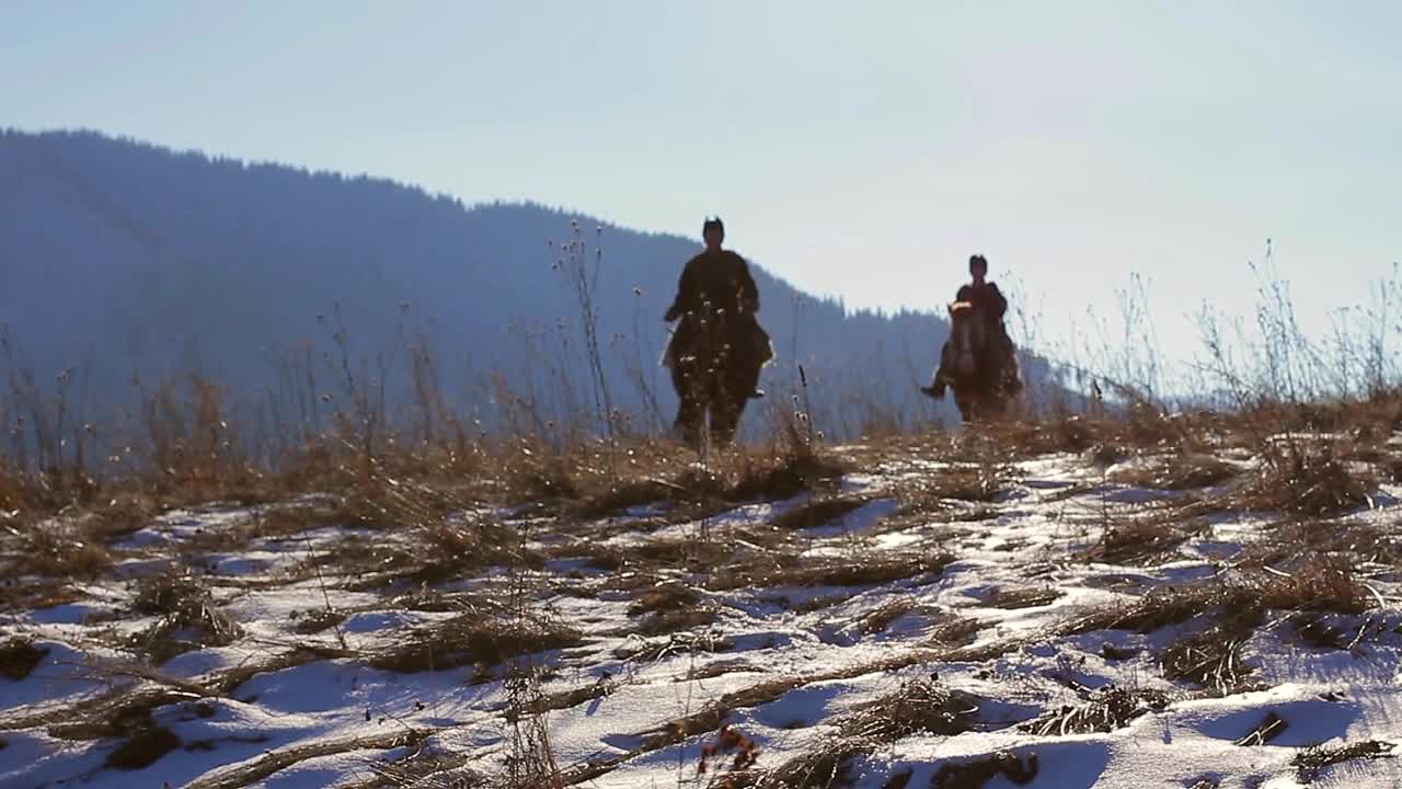 Two horsemen patrol the border in the mountains. Highlands