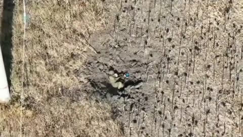 A Russian soldier lying in a crater is shocked by a drone strike that did not