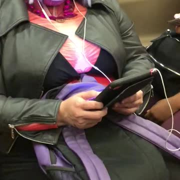 Woman in costume and blonde wig on phone on train