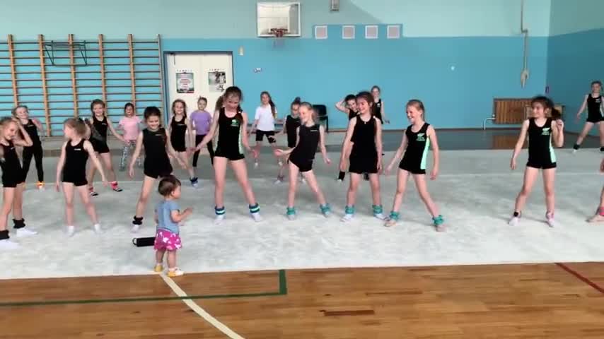 Gymnasts have fun imitating the dance moves of a little girl