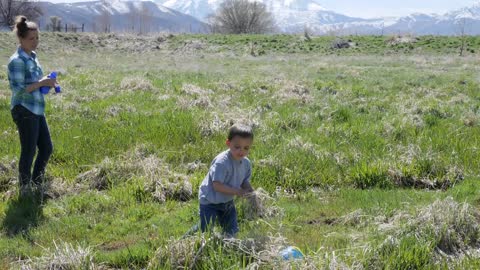 A Mother And Boy Hunting For Frogs In A Swampy Green Field In The Spring