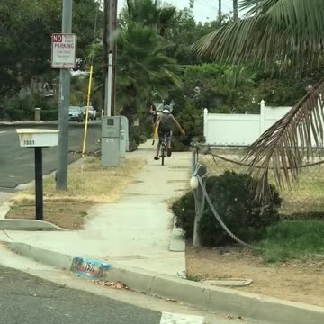 Guy yellow boogie surf board riding down street on unicycle