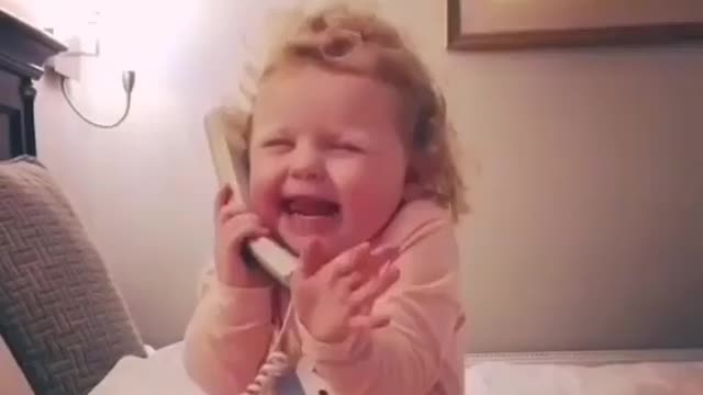 A small child talking on the telephone.