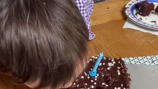 Little boy takes a bite of cousins birthday cake.