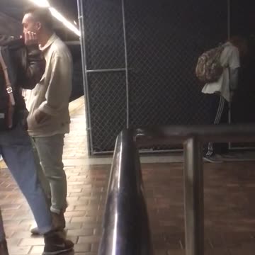 Blonde guy camo backpack dancing in front of fence subway