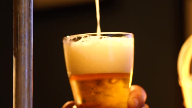 Bartender serving beer from a tap looking down at his hands