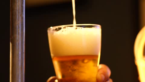 Bartender serving beer from a tap looking down at his hands