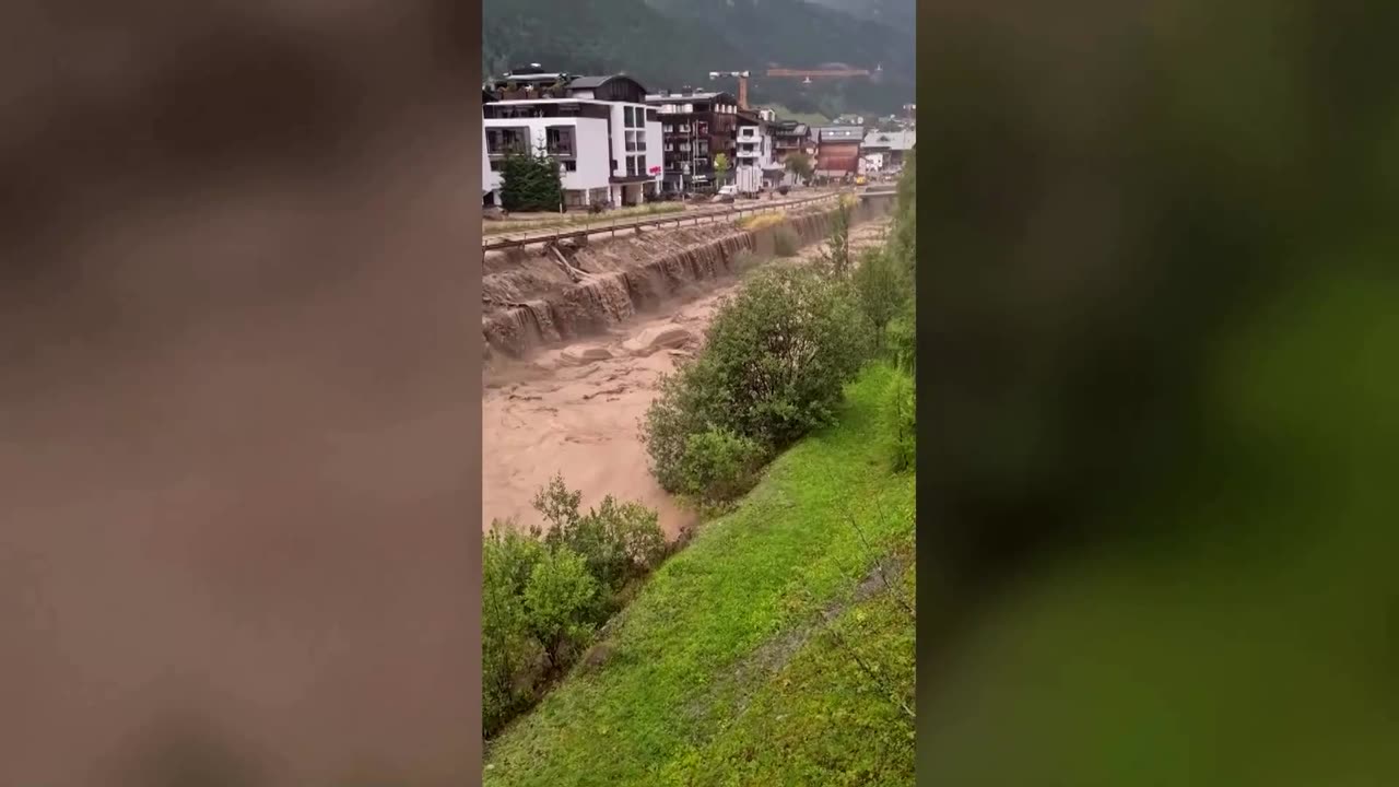 Raging muddy water carry cars through Austrian ski resort