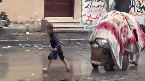 Palestinian children carrying their only belongings in the rain