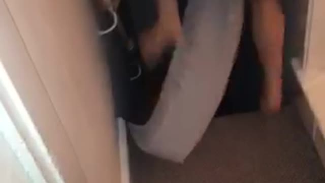 Shirtless guy rides mattress sideways down stairs