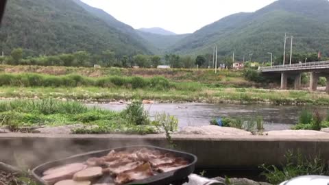 Grilling and eating pork belly by the summer valley