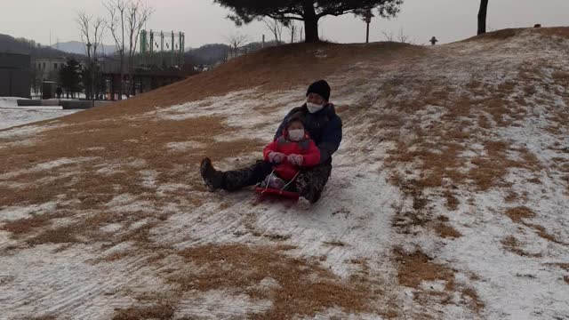 Baby and Dad sledding in the park