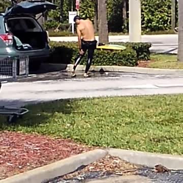 Surfer washes himself with gallon of water in parking lot