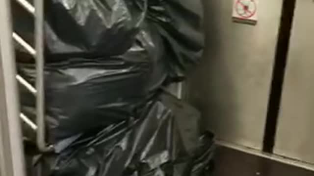 Black trash piled up man in cardboard boxes