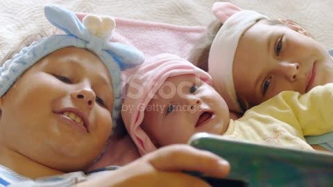 children together with the baby watch video on the smartphone