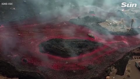 Drone view of La Palma house engulfed by lava & hot boulders