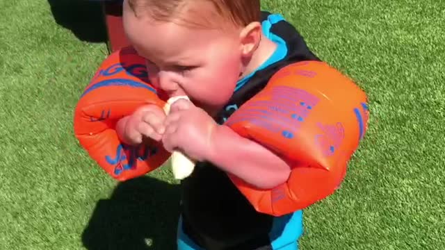 Baby Makes Hilarious Attempts To Eat A Banana While Wearing Floaties