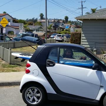 Smart car with surf board in the back of car