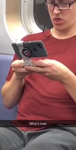 Man in red shirt has phone on a grey stand
