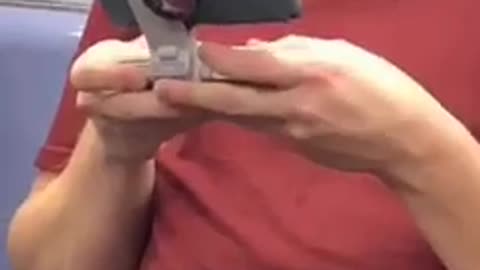 Man in red shirt has phone on a grey stand