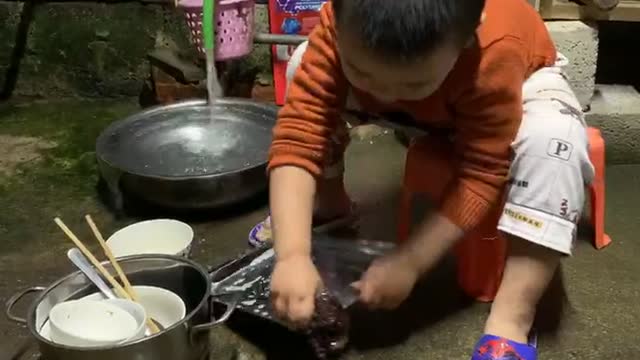 Lovely boy washing dishes for mom