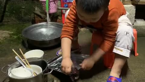 Lovely boy washing dishes for mom