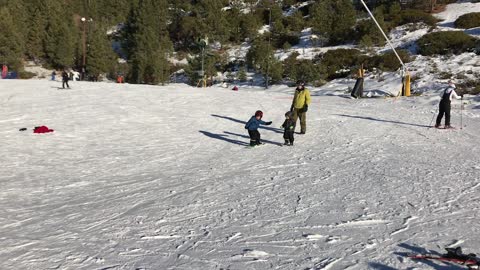 My 5 years old boy snowboarding and his brother running after him