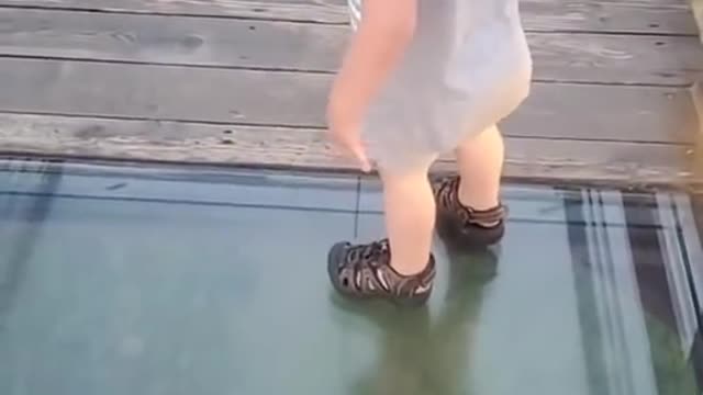 Little boy attempts to cross onto glass bridge