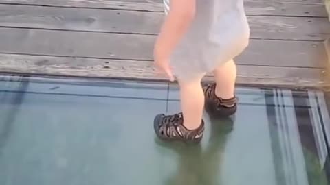 Little boy attempts to cross onto glass bridge