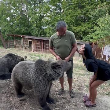 A girl feeds a bear from her mouth