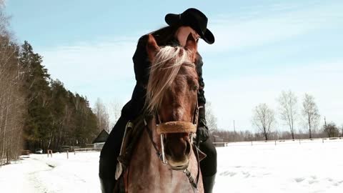 girl cowboy sitting on a horse in winter