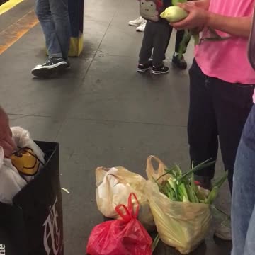 Woman tearing corn husks on subway station