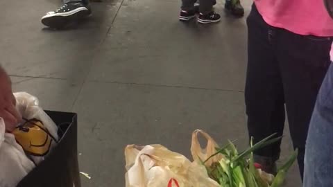 Woman tearing corn husks on subway station