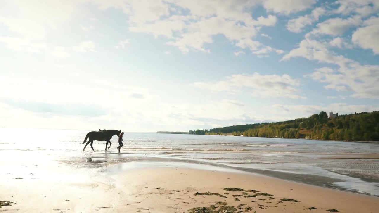 a young girl walks on the beach with a horse