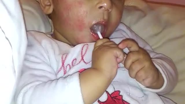 A little baby sucking a lollipop