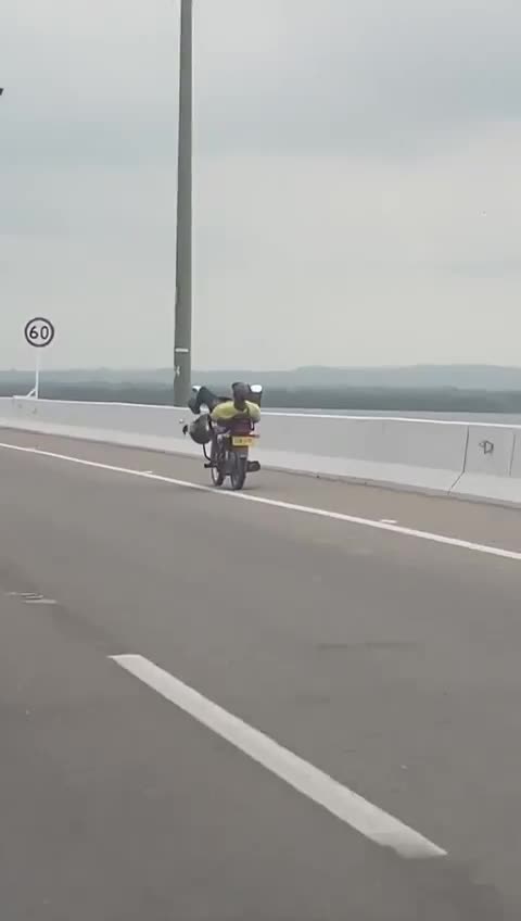 Irresponsable al volante: motorizado conduce una moto con las piernas en el viaducto