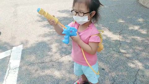 a little girl playing with a water gun