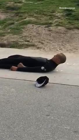 Guy surfer on beach stretching with legs folded back on sidewalk