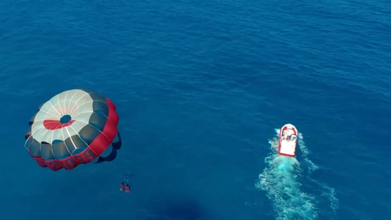 Couple's Thrilling Paragliding over Blue Sea