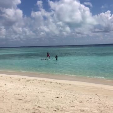 Guy red shorts surfboard friend in water taking picture