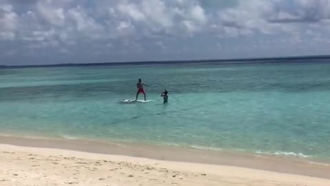 Guy red shorts surfboard friend in water taking picture