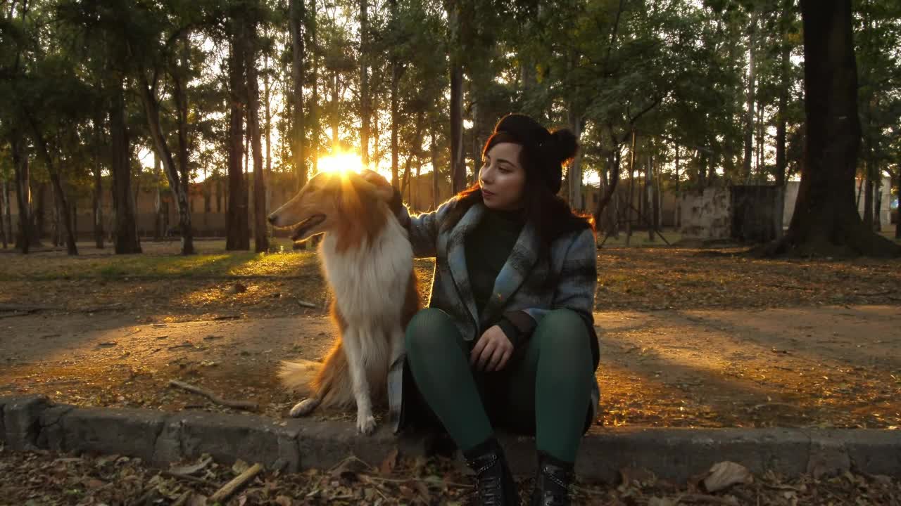 A woman pets a dog in a park