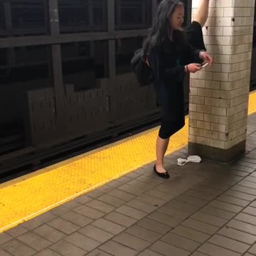 Woman puts foot above head and texts on subway platform