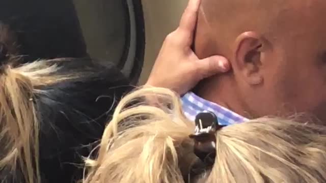 Lady massaging back of head of bald guy subway