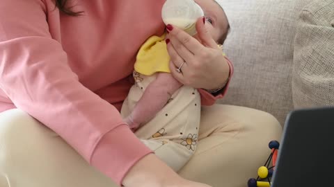 A Mother Feeding Her Baby while Using a Laptop