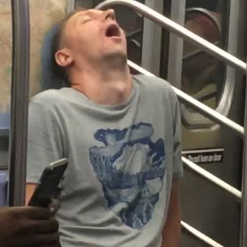 Man in grey shirt asleep with mouth wide open