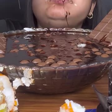 A TUB OF HOT CHOCOLATE WITH CHOCOLATE EGGS, CHOCOLATE BARS, CHOCOLATE WAFFLE, CHOCOLATE CAKES,EATING